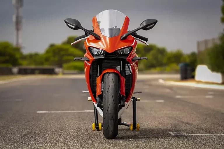 Red KOVE sportbike shot head-on, resting on paddock stands on the asphalt of a closed road