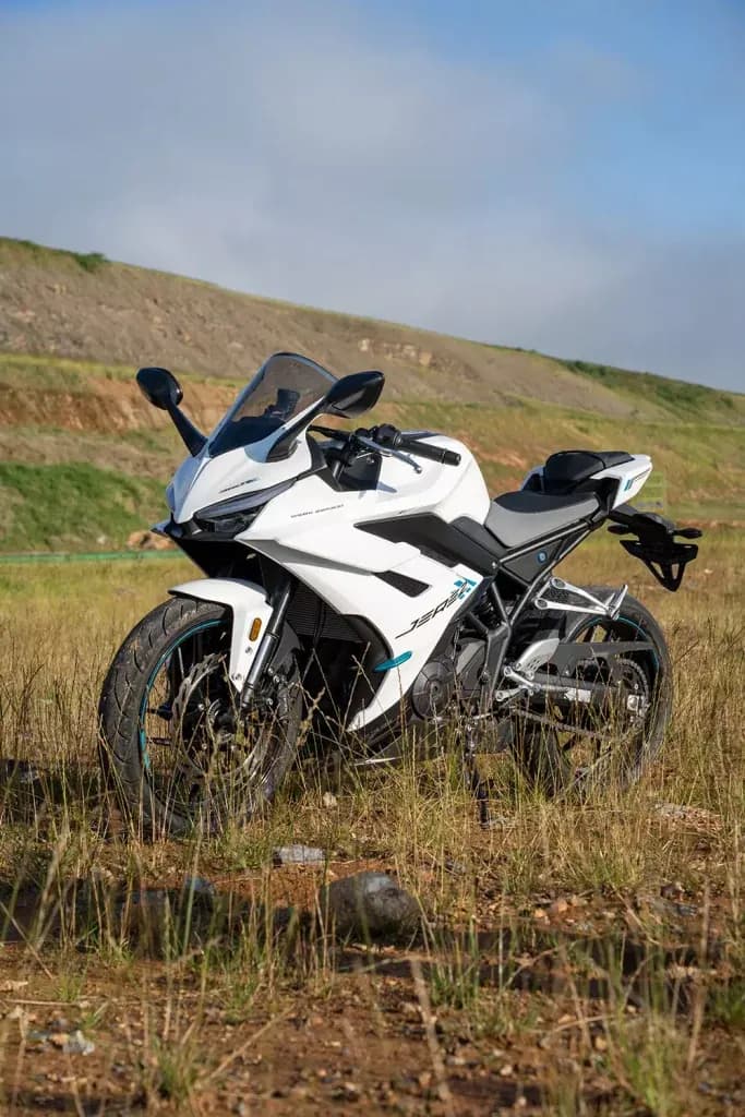 White KOVE sportbike with teal accents, parked on dry grass