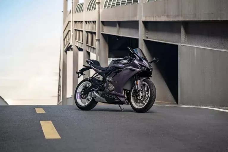Metallic purple KOVE sportbike parked on a road beside a large concrete building