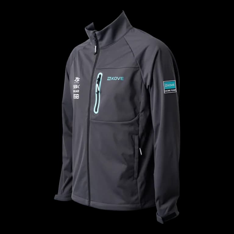 Dark grey softshell jacket with a teal KOVE logo, teal-zipped chest pocket and a “KOVE Racing Team” sleeve patch