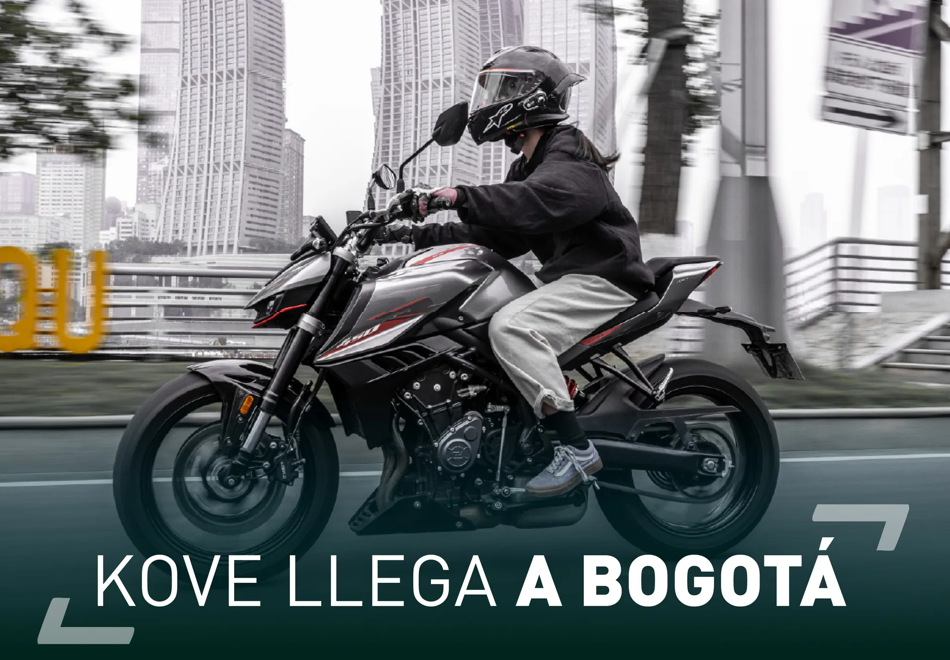 Rider in a full-face helmet on a KOVE naked bike along a city avenue, skyscrapers behind, with the headline «KOVE llega a Bogotá» — KOVE arrives in Bogotá — set over the image